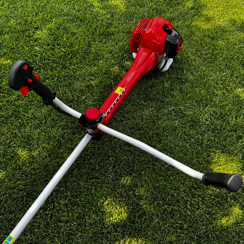 Desbrozadora Dece Pro 63 CC Doppia roja sobre césped. Herramienta de jardinería potente y eficiente.